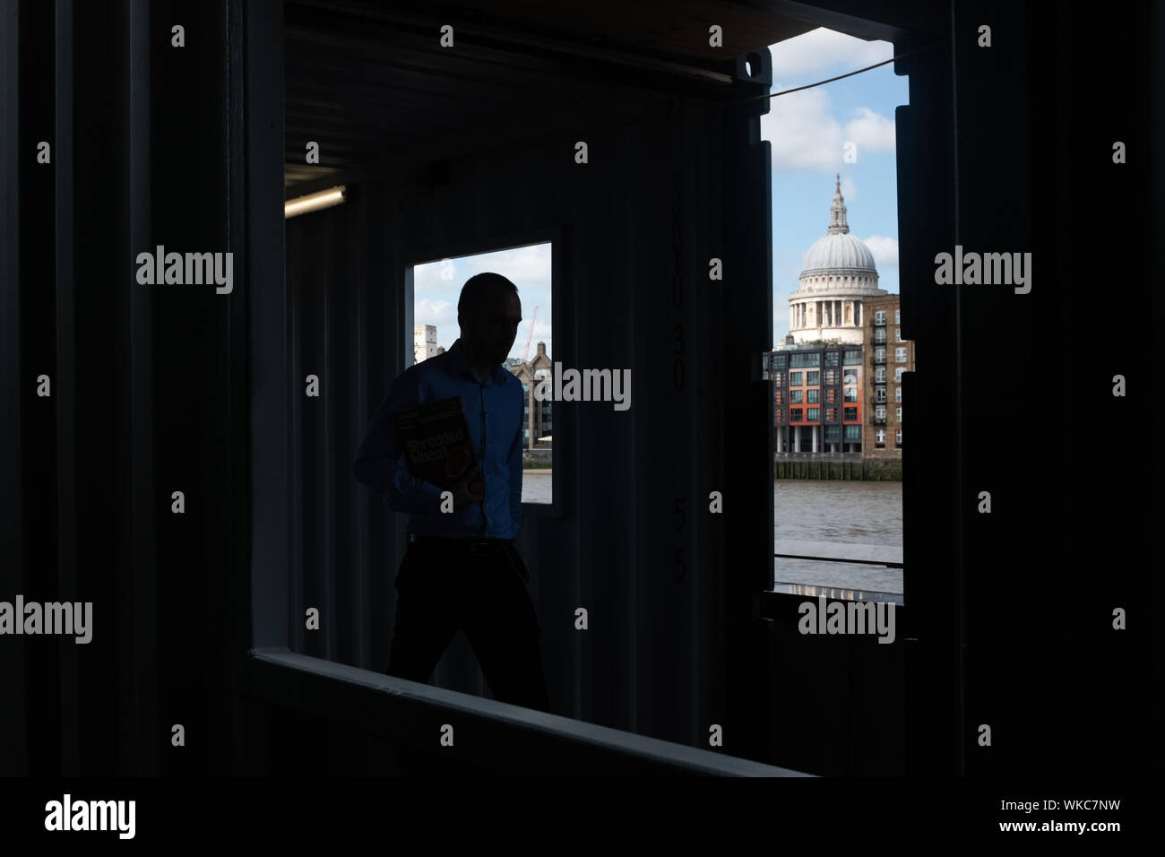 Ein Mann Spaziergänge entlang der Uferstraße entlang der Themse in London, St Paul's Kathedrale im Hintergrund. Stockfoto