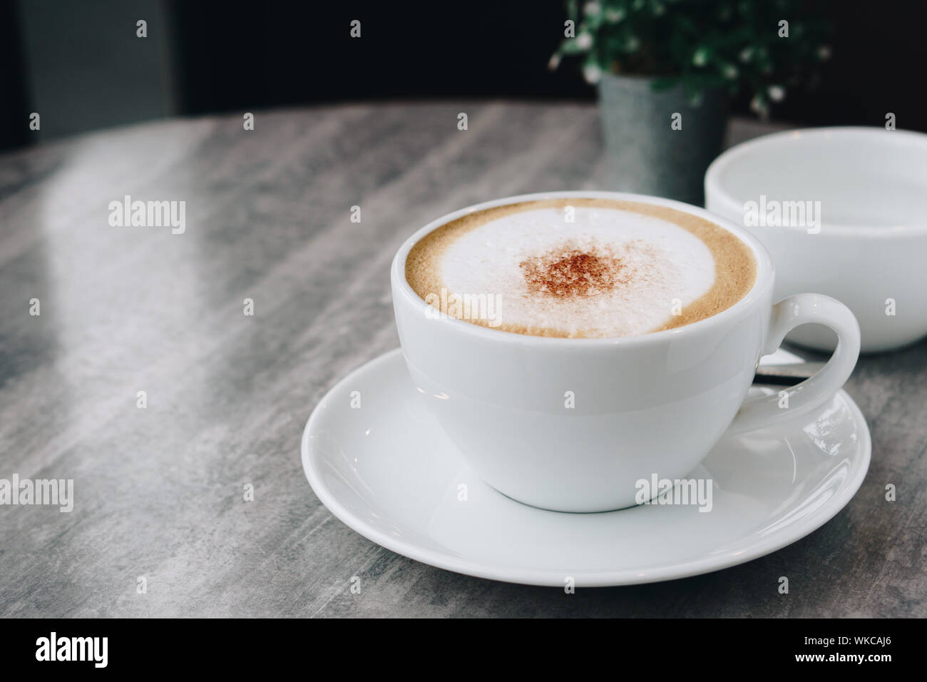 Heißer Kaffee, heißen Tee und Blumenvase mit grünen Blättern auf dem marmortisch am frühen Morgen mit Kopie Raum, weißer Schale und silbernen Löffel. Stockfoto