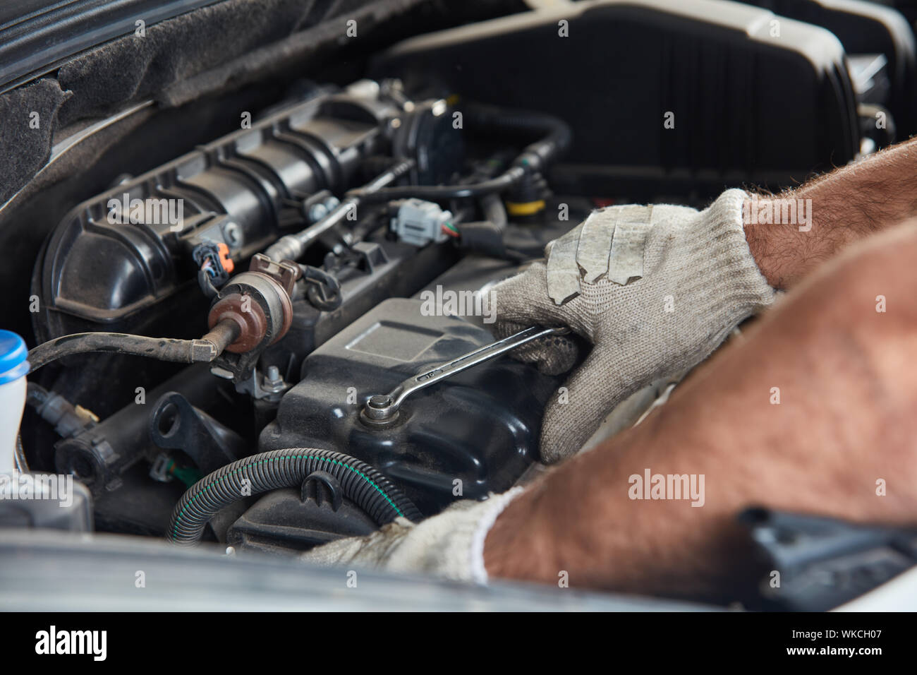 KFZ Mechaniker repariert Motor eines Fahrzeugs in der Autowerkstatt - Close  Up Hand mit Werkzeug im Motorraum Photos