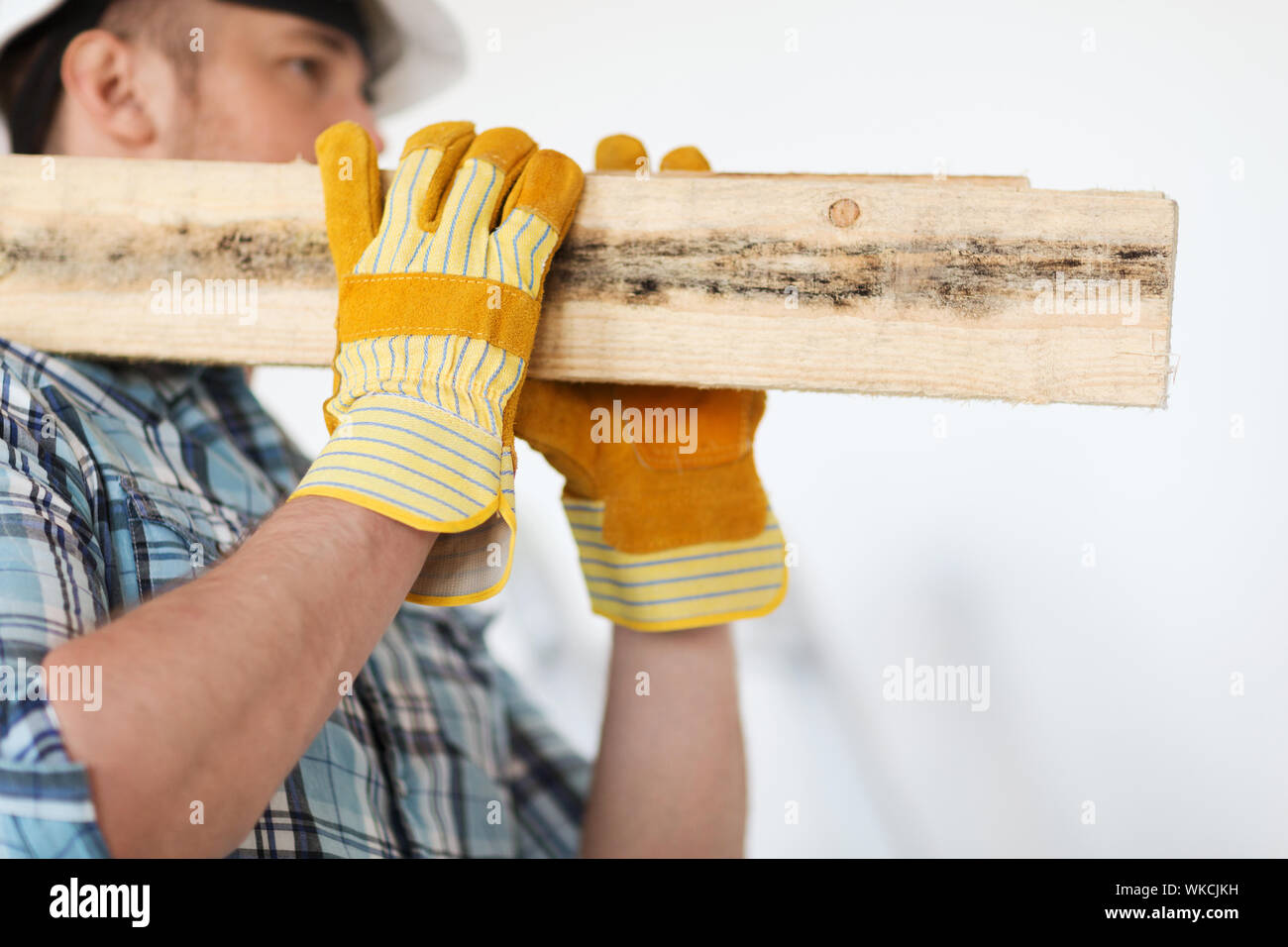 Reparatur, Aufbau und Konzept home - Nahaufnahme von männlich in Handschuhe und Helm tragen Holzbretter auf Schulter Stockfoto