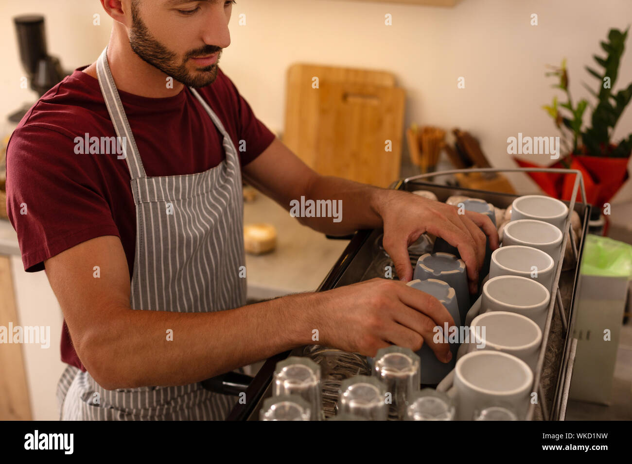 Stattliche Barista. Stattliche barista tragen gestreifte Schürze, cups auf Kaffeemaschine Stockfoto