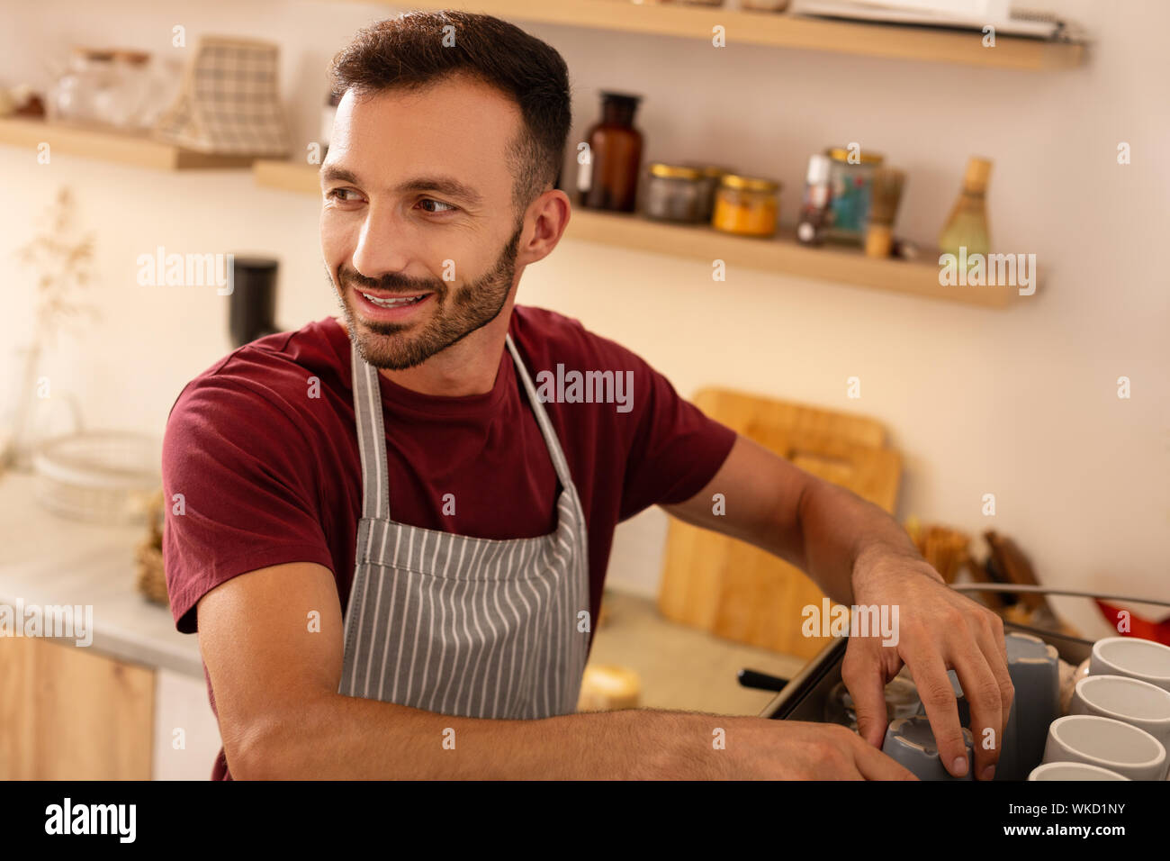 Spaß an der Arbeit. Dark-eyed barista Schürze tragen, seinen Arbeitstag sehr genießen. Stockfoto