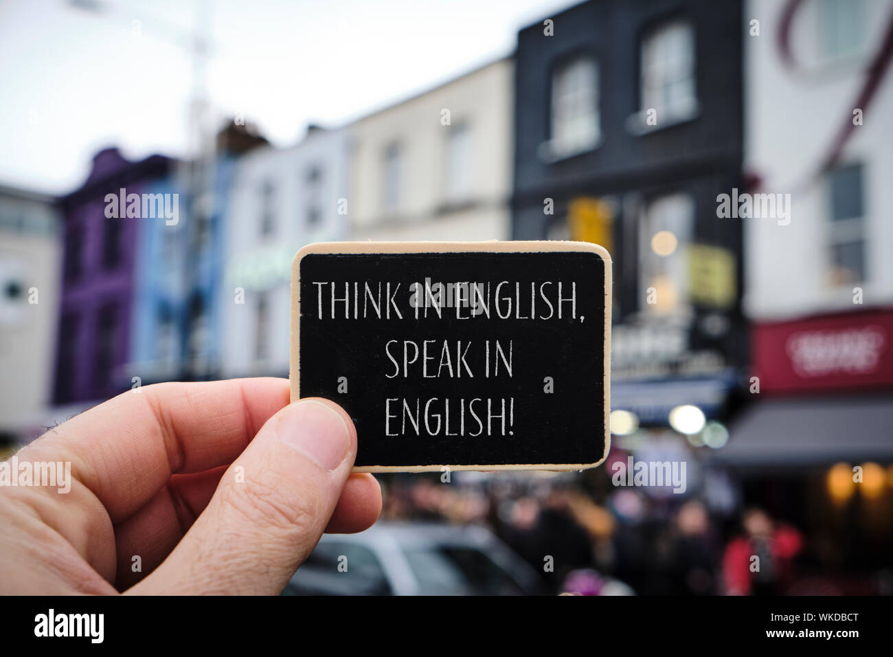 Nahaufnahme der Hand eines kaukasischen Mann mit einem schwarzen Schild mit dem Text Denken, Englisch sprechen, Englisch in Es geschrieben, auf der Straße, in den pop Stockfoto