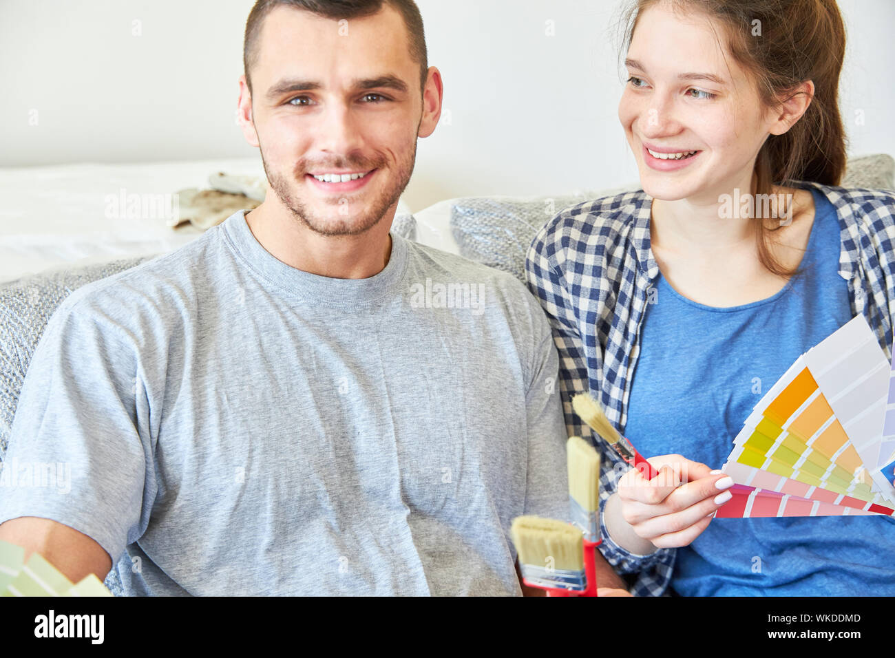 Junges Paar als Home Improvement mit Pinsel und Farbe Lüfter bei der Wahl der richtigen Wandfarbe Stockfoto