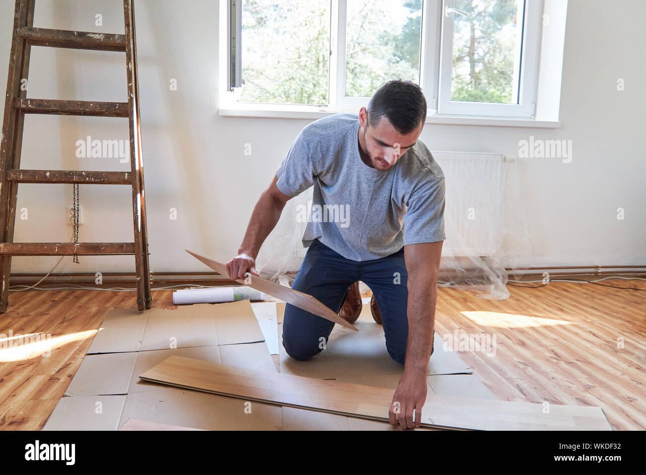 Der Mensch als Handwerker oder Do-it-yourself-Arbeitnehmer Verlegung Parkett in der neuen Wohnung Stockfoto