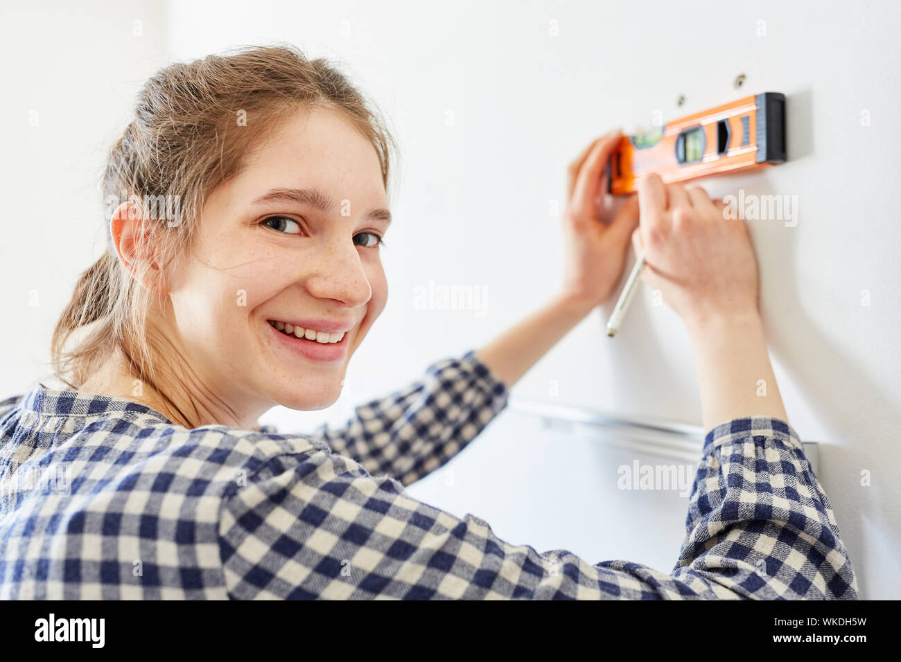 Junge Frau als DIY home Verbesserung während der Messung mit der Wasserwaage an der Wand Stockfoto