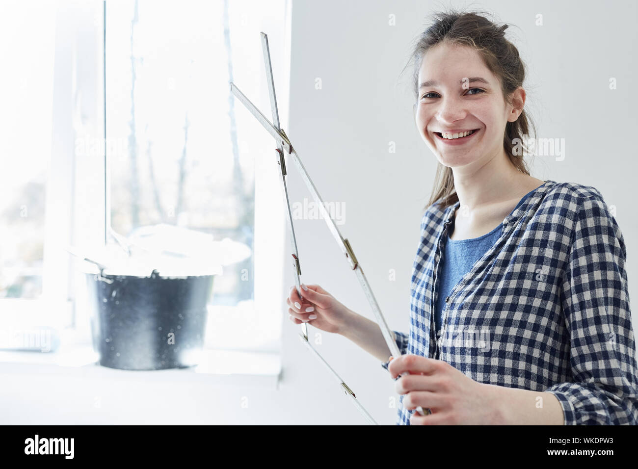 Glückliche junge Frau als Heimwerker mit Zollstock, während Ihre neue Wohnung renovieren Stockfoto