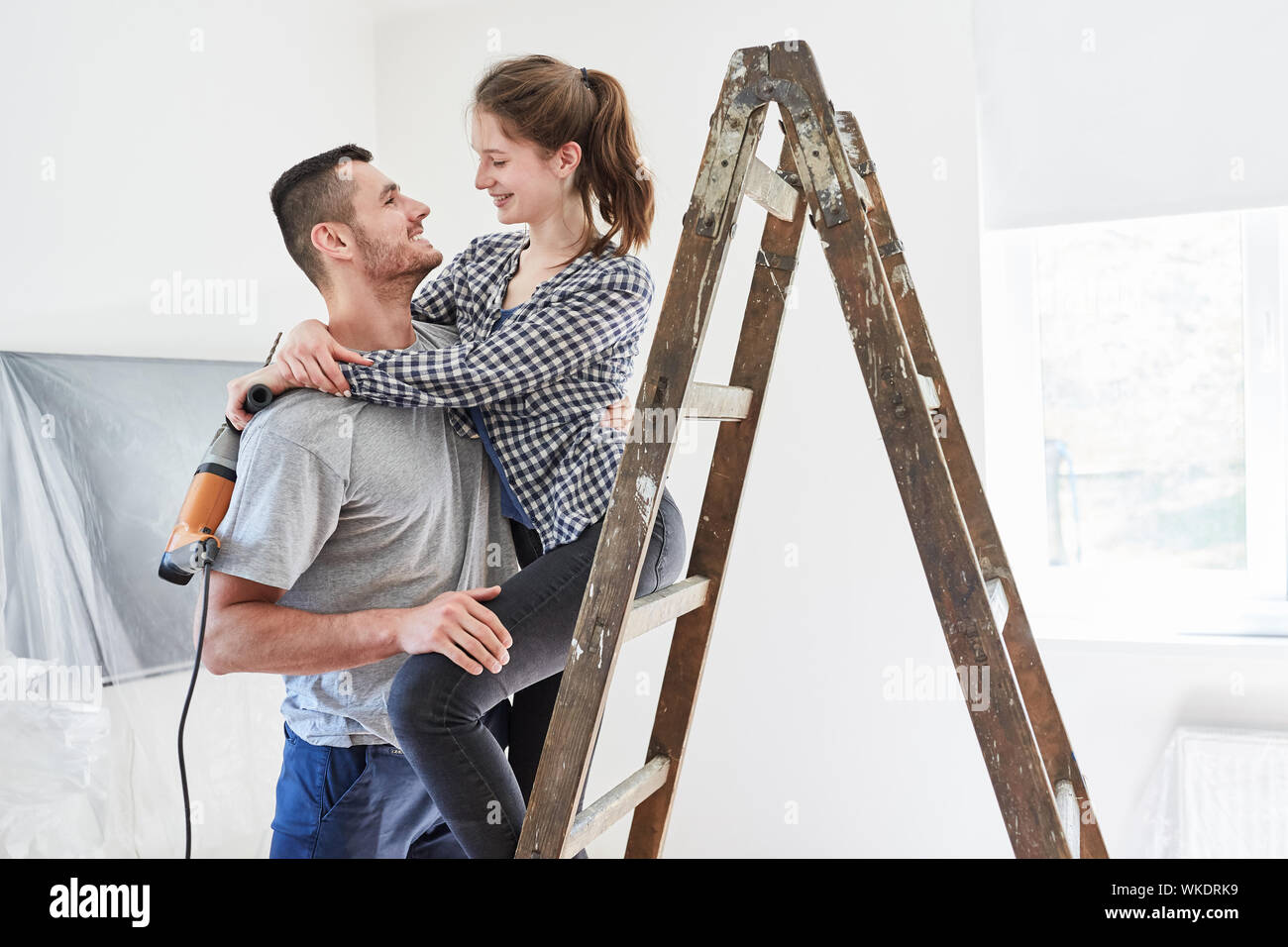 Verliebter junge Paar zusammen im neuen Haus renovieren mit Leiter Stockfoto