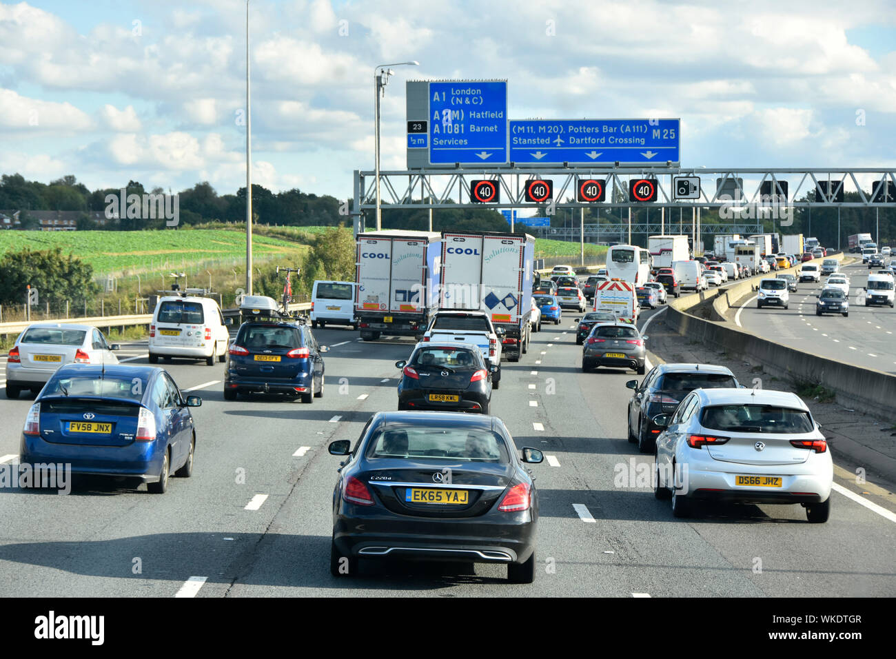 Verkehr M25 Autobahnkurve & blaue Route Straßenschild über der Gantry elektronische Schilder mit variabler Geschwindigkeit, eingestellt auf 40 MPH Freitag PM Rush Hour London England UK Stockfoto