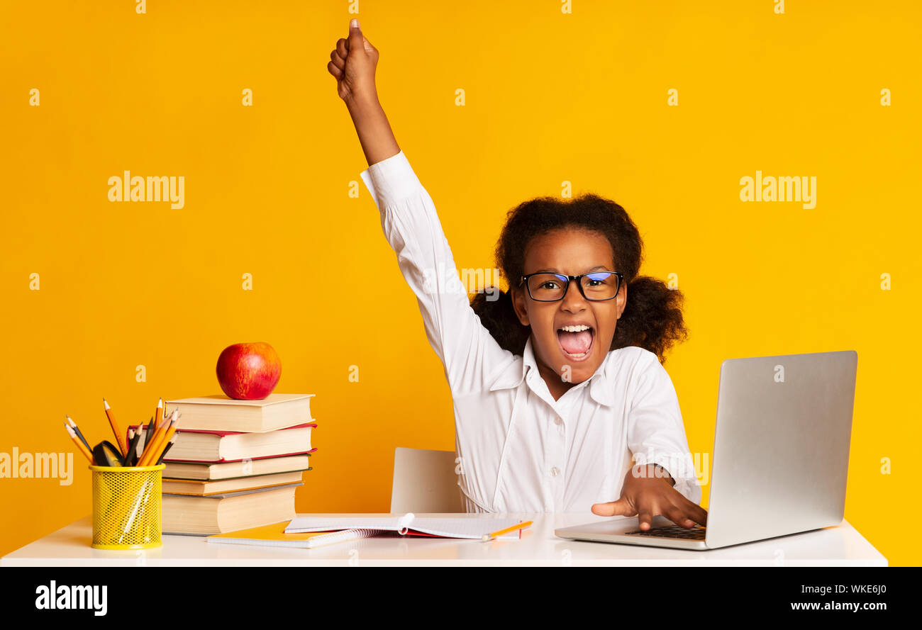 Afro Schulmädchen heben die Hand am Laptop im Studio Stockfoto