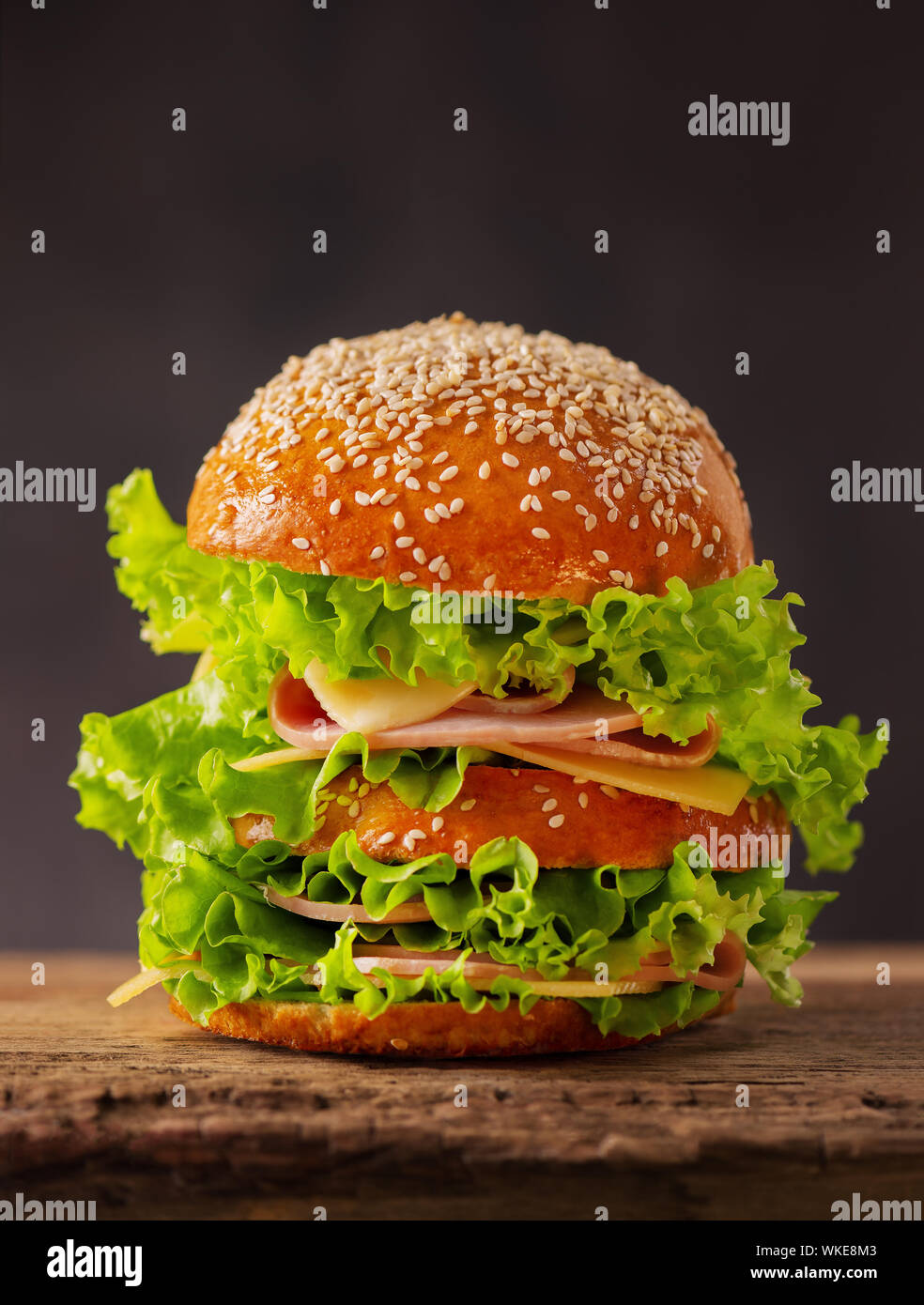 Big Sandwich Burger mit Käse, Schinken und Salat auf einem dunklen Hintergrund. Stockfoto