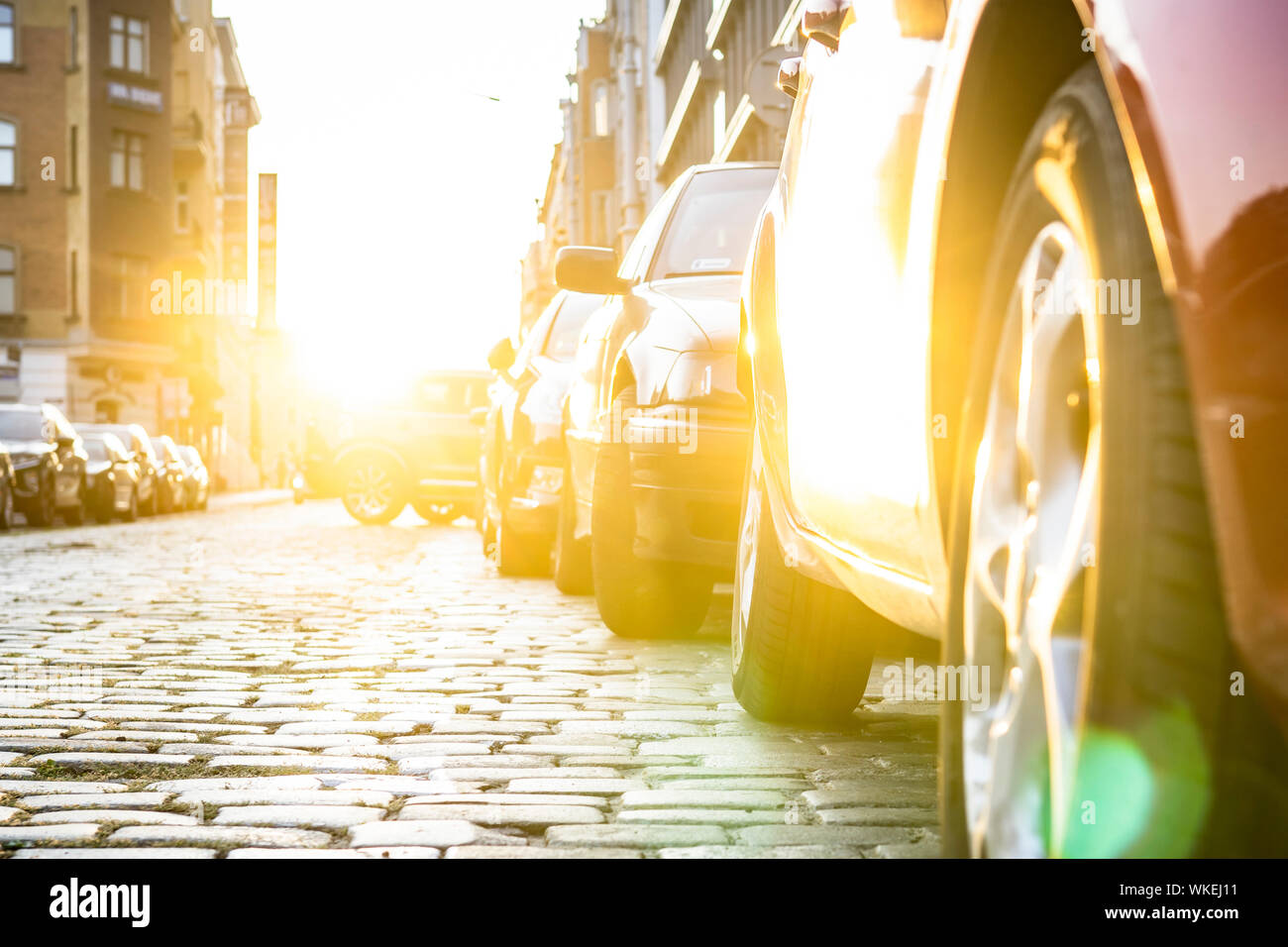 Autos auf einer asphaltierten Straße mit einer Sonne geparkt. Stockfoto