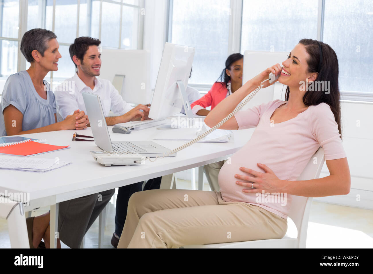 Geschäftsfrau am Telefon und Anschläge preganat Bauch im Büro Stockfoto