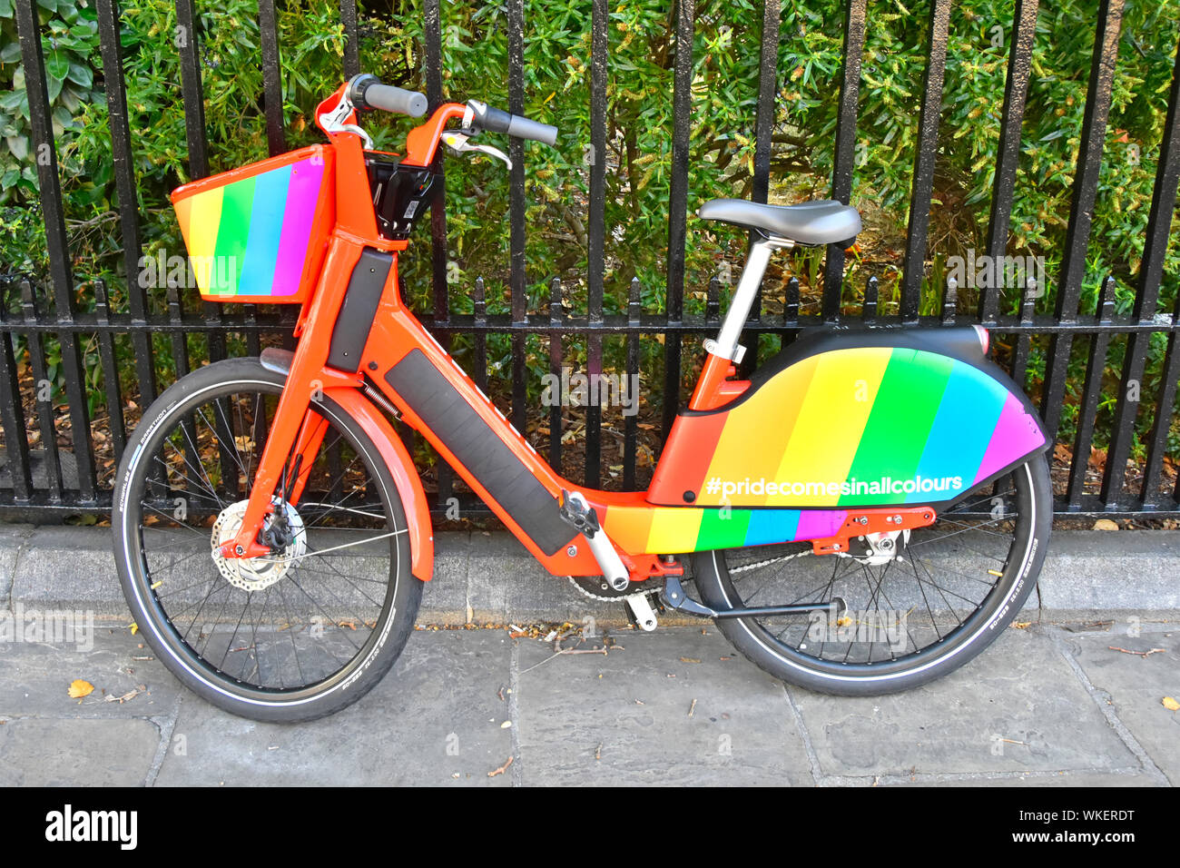 Bunte Fahrrad in Gay Pride Regenbogen Flagge Farben auf einem Uber GPS app Tracker electric pedal Jump bike neben Geländer London England UK geparkt unterstützen Stockfoto