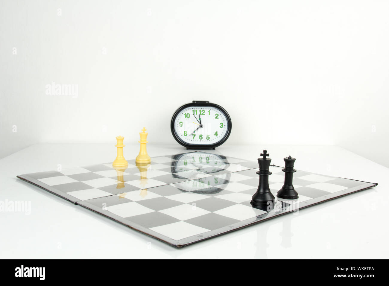 Schachfiguren auf einem karierten Brett mit Uhr Stockfoto