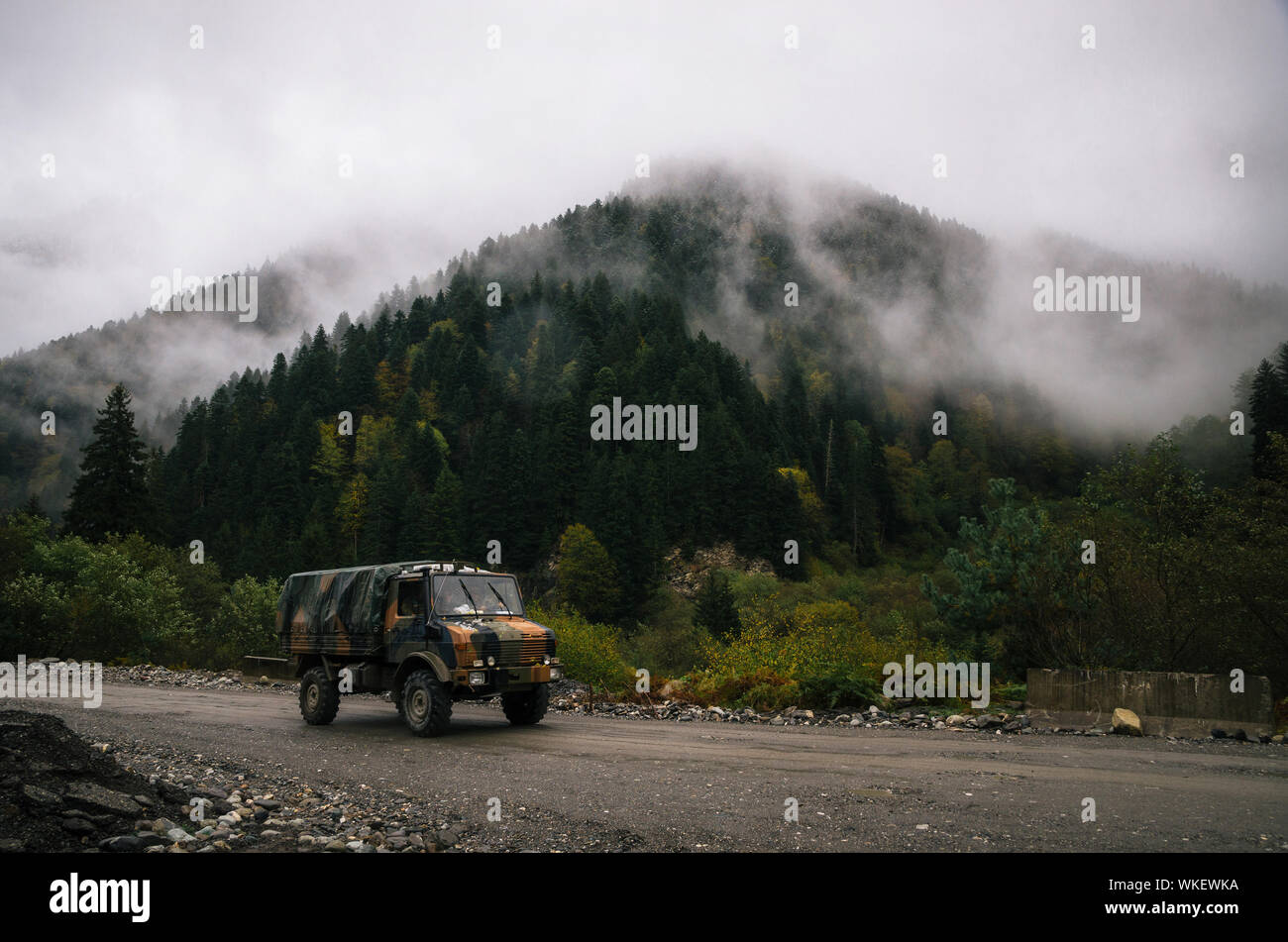 Militär-Lkw der Streitkräfte aus Georgien treibt in der Nähe der Grenze zu Südossetien gegen die verschneite Bäume im Nebel Wolke auf dem Berg Stockfoto