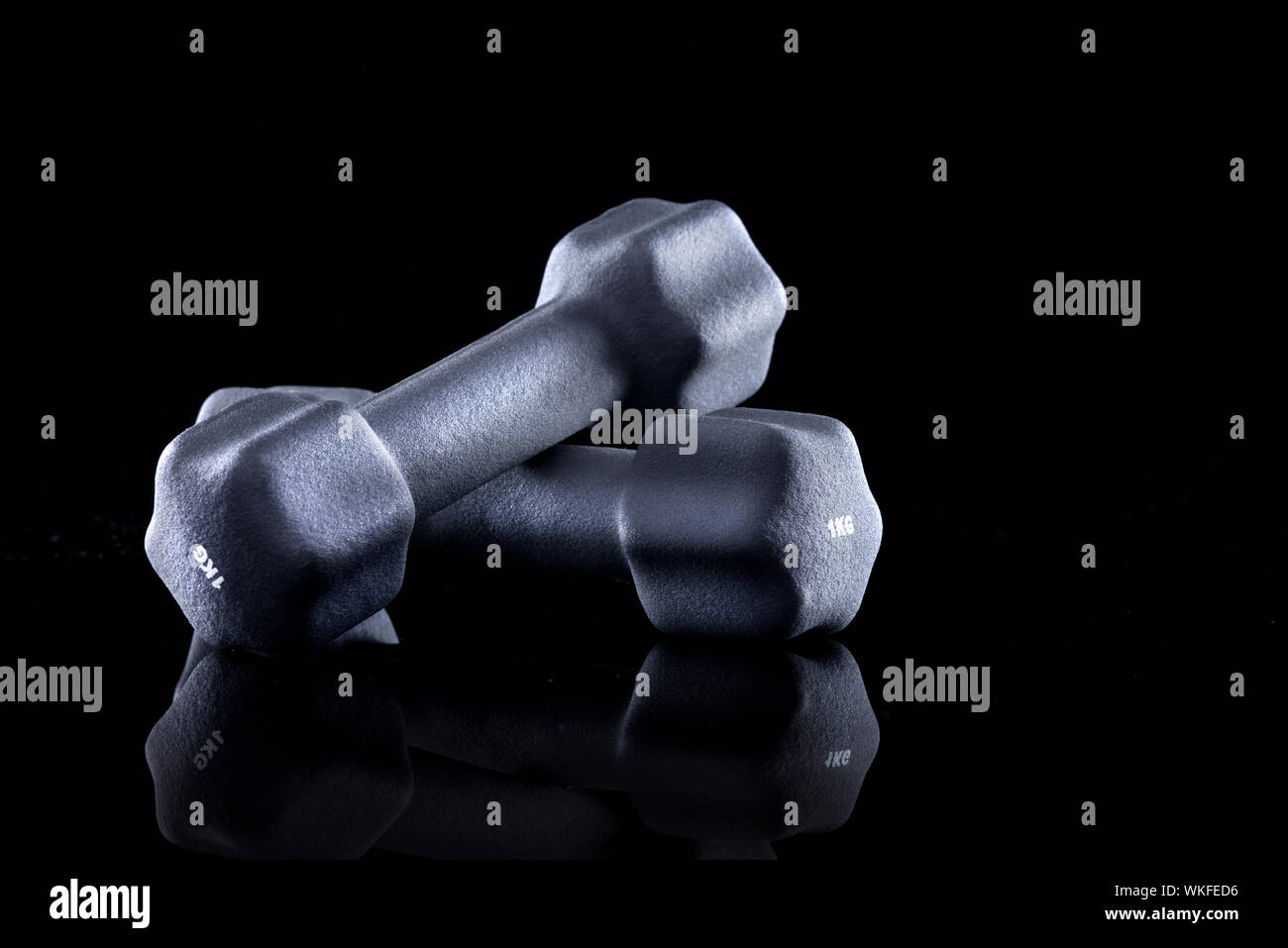 1 kg Hanteln für Krafttraining auf schwarzem Hintergrund. Stockfoto