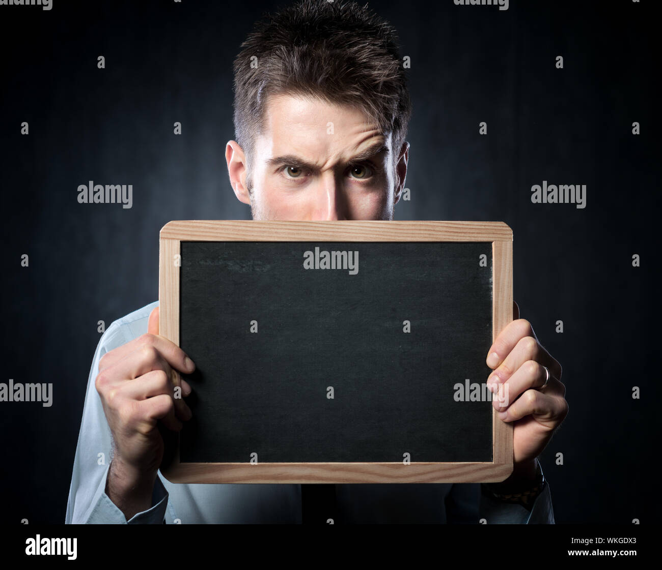 Schönen jungen Mann mit hochgezogenen Augenbrauen hält eine Tafel. Stockfoto