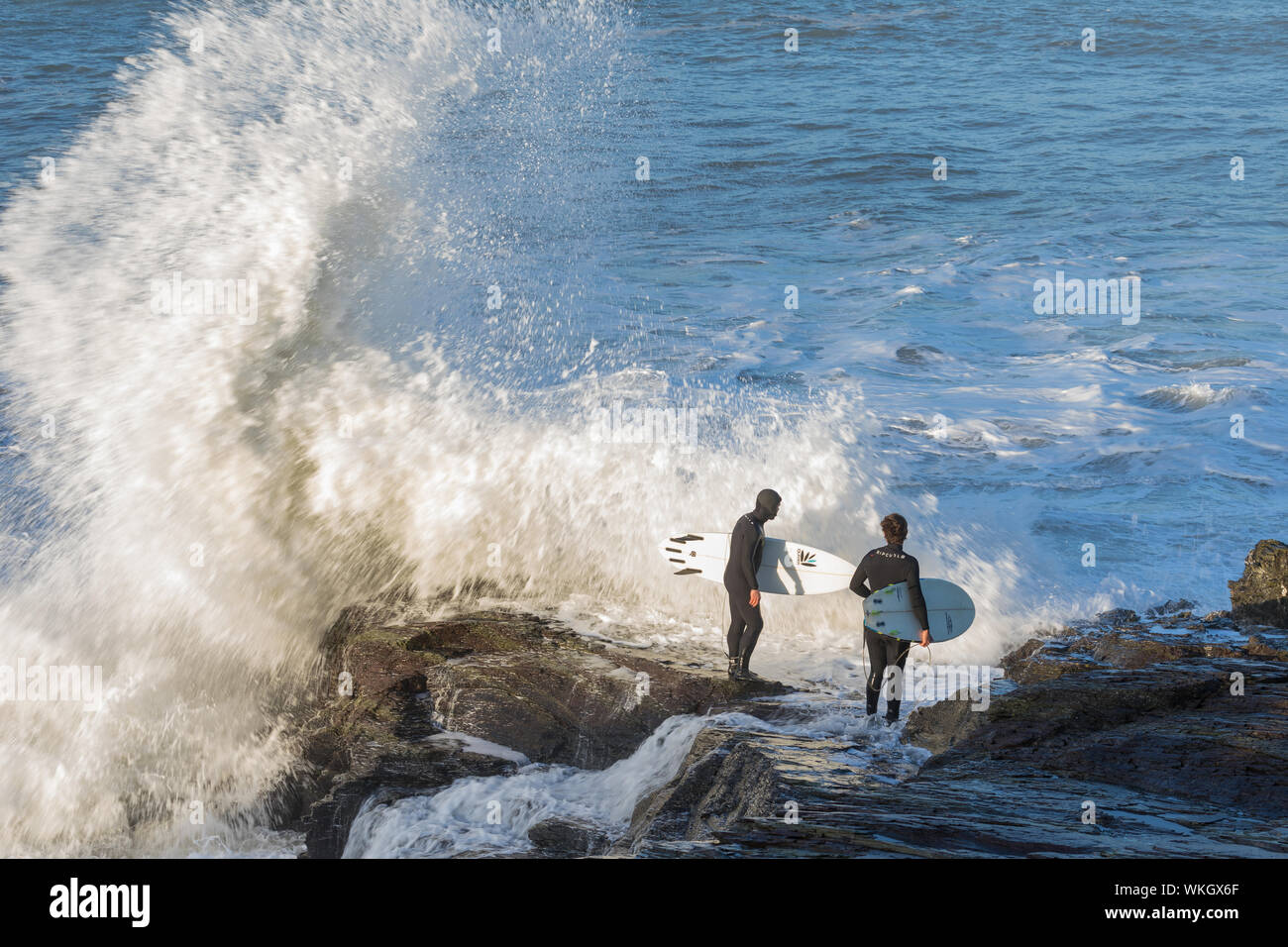 Polzeath, Großbritannien - Jan 06, 2018: Zwei Surfer versucht, einen Weg, auf dem Meer, von den Felsen zwischen Polzeath und daymer finden. Wellen sind Absturz in die Felsen Stockfoto