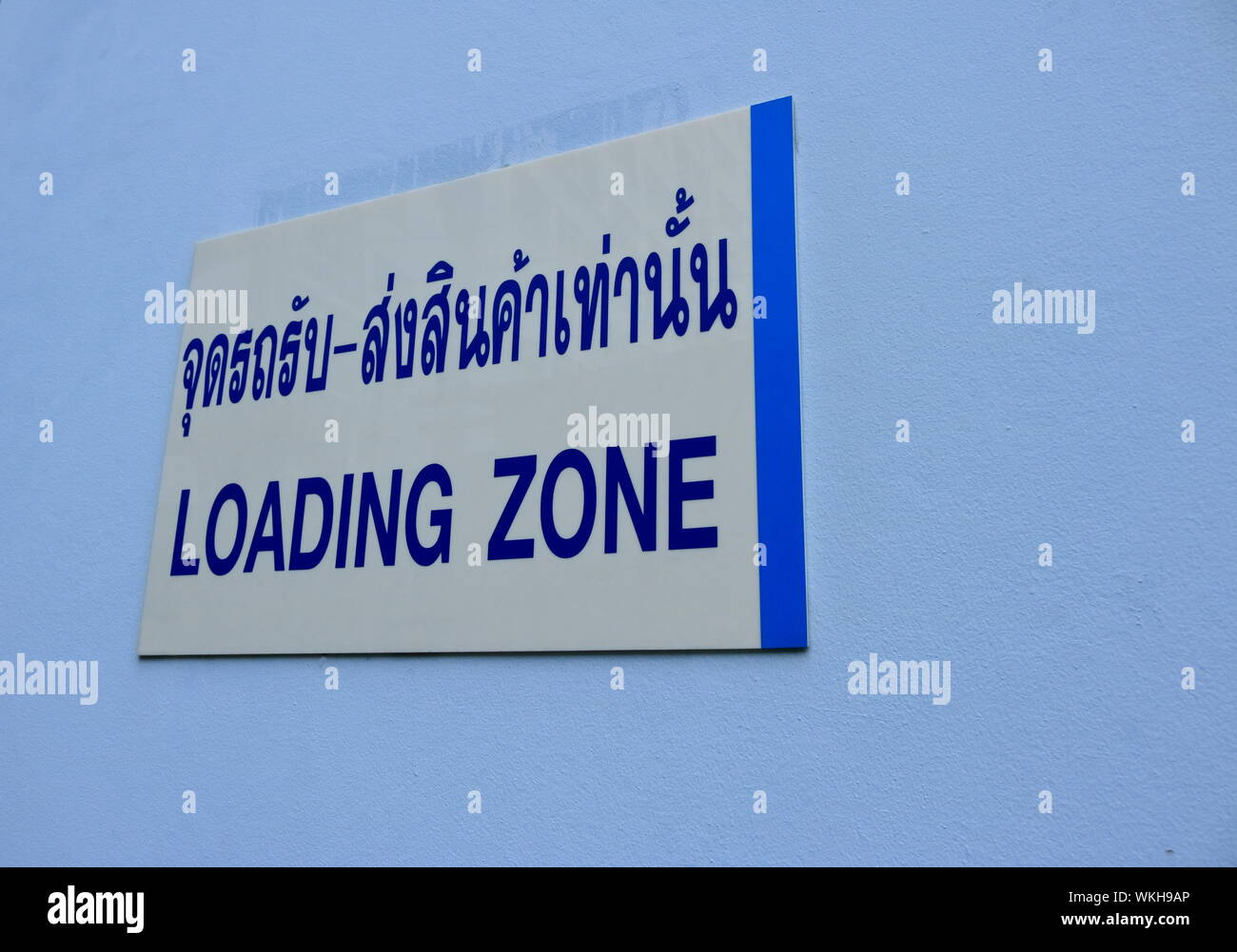 Nahaufnahme der Ladezone Zeichen sowohl in Thai und Englisch Sprache Installation auf blauen Beton Wand eines Gebäudes Stockfoto