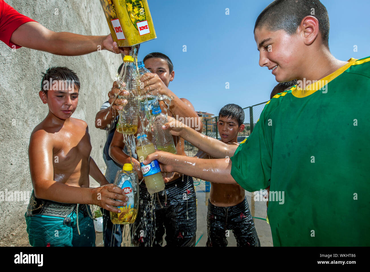 Junge Wrestler versuchen, so viel canola Öl in Flaschen wie möglich an die Elmali türkisches Öl Wrestling Festival in Elmali in der Türkei zu sammeln. Stockfoto