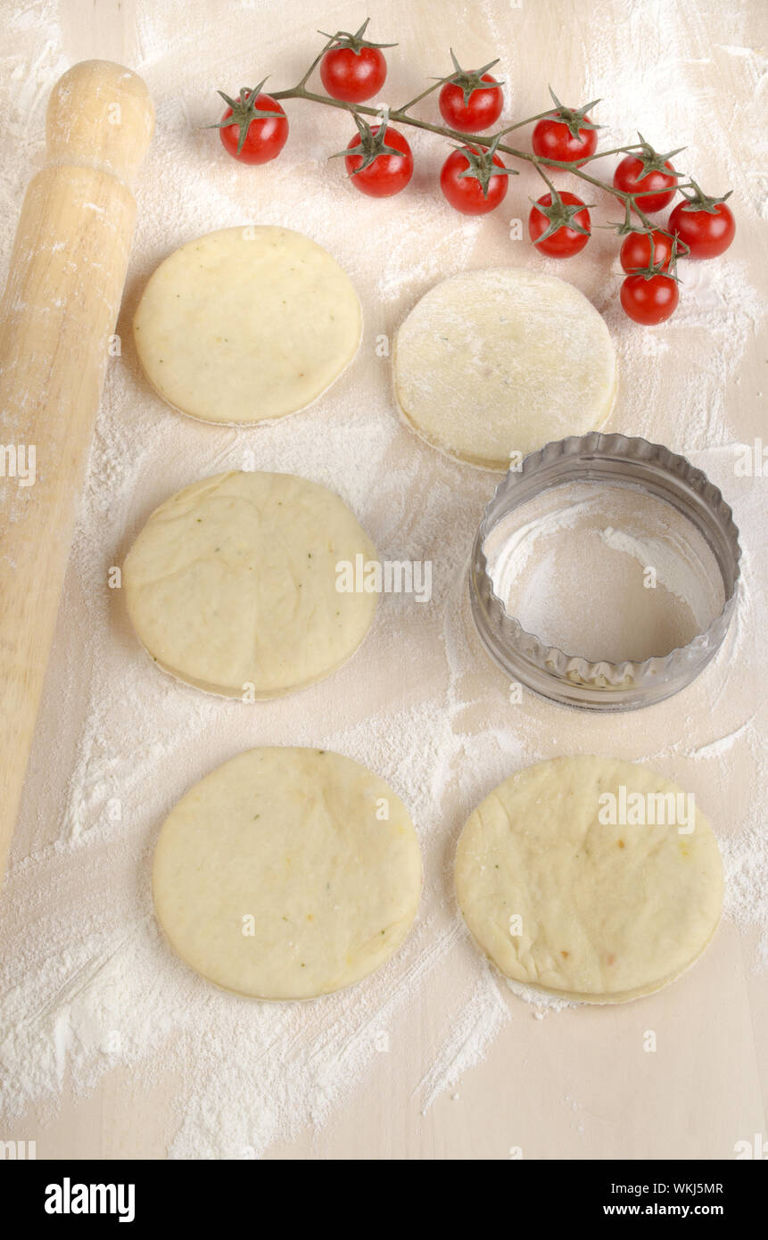 würzige Mini Pizzateig auf einer mehligen Holzbrett Stockfoto