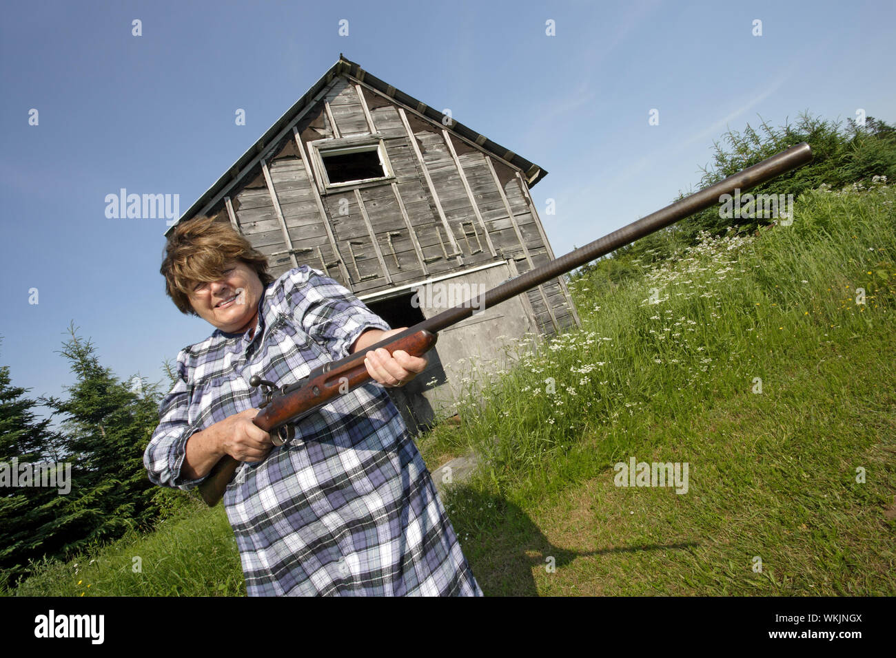 Foto von eine ältere Frau mit einem großen Gewehr. Stockfoto
