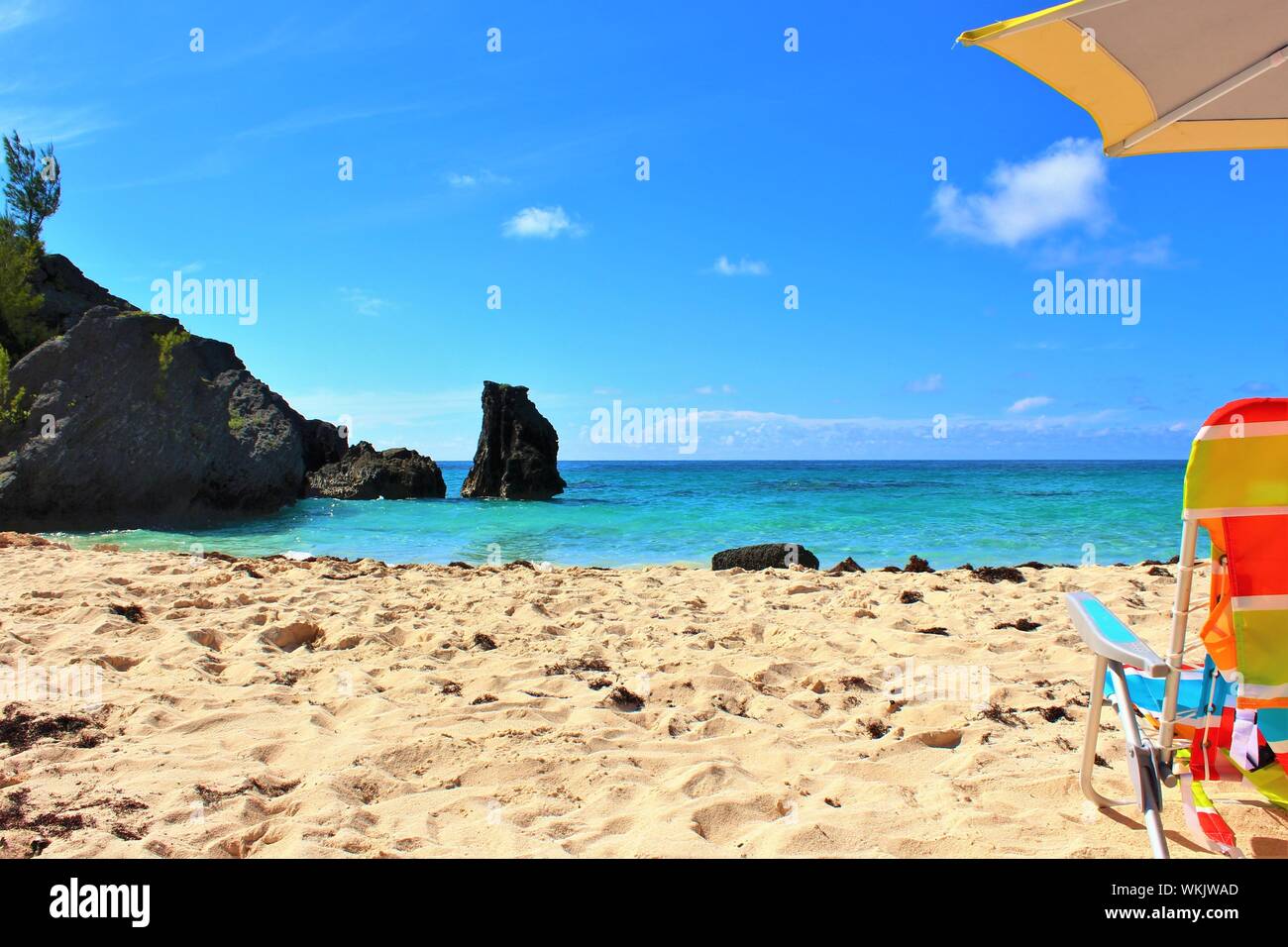 Konzeptionelle Schuß eines idyllischen Urlaubsort. Ein abgeschiedener, Paradise Beach in Bermuda, mit Sonne, türkisfarbenes Meer, weißer Sand, Sonnenschirm und Liegestuhl. Stockfoto