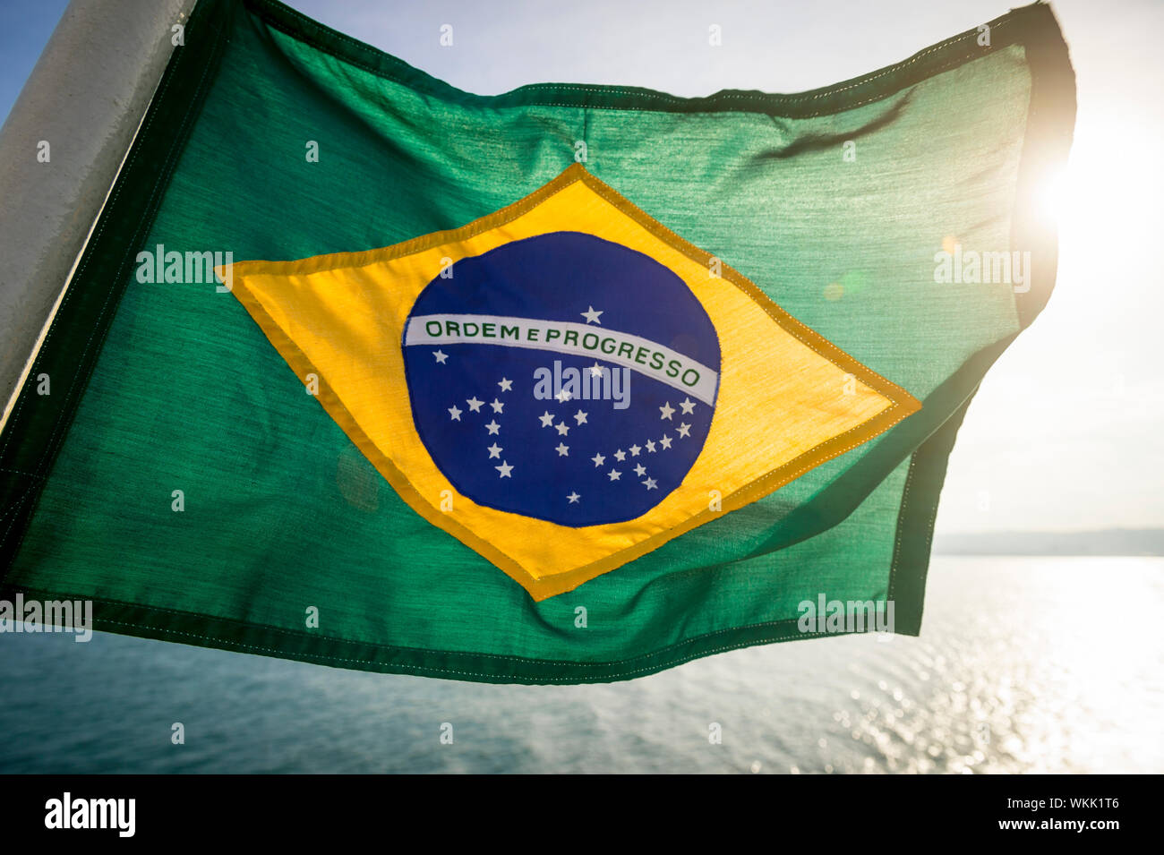 Golden Hintergrundbeleuchtung Blick auf dicke texturierte Flagge von Brasilien fliegen im Freien in tropischen brasilianischen Sonnenlicht Stockfoto