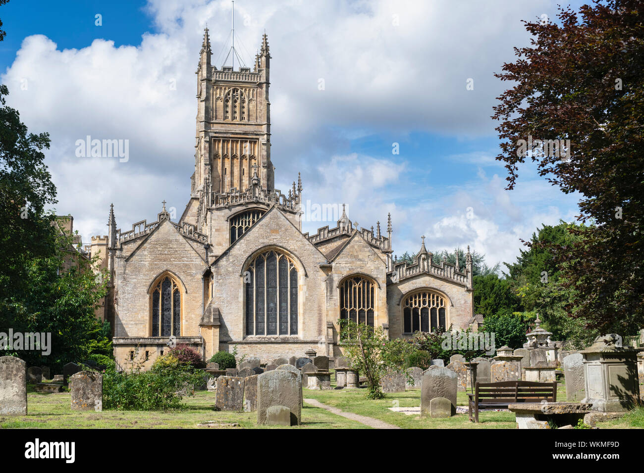 Die Kirche St. Johannes der Täufer aus dem Garten der Erinnerung. Cirencester, Cotswolds, Gloucestershire, England Stockfoto