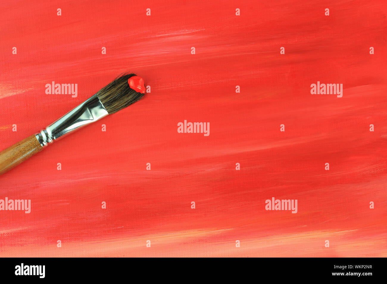 Pinsel gegen eine rote abstrakte Malerei. Stockfoto