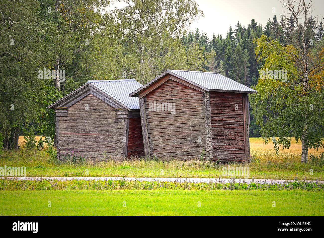 Zwei kleine, schiefe Scheunen oder Ställen in der finnischen Landschaft im Spätsommer. Jalasjärvi, Osthrobotnia, Finnland. HDR, Licht filtern. Stockfoto
