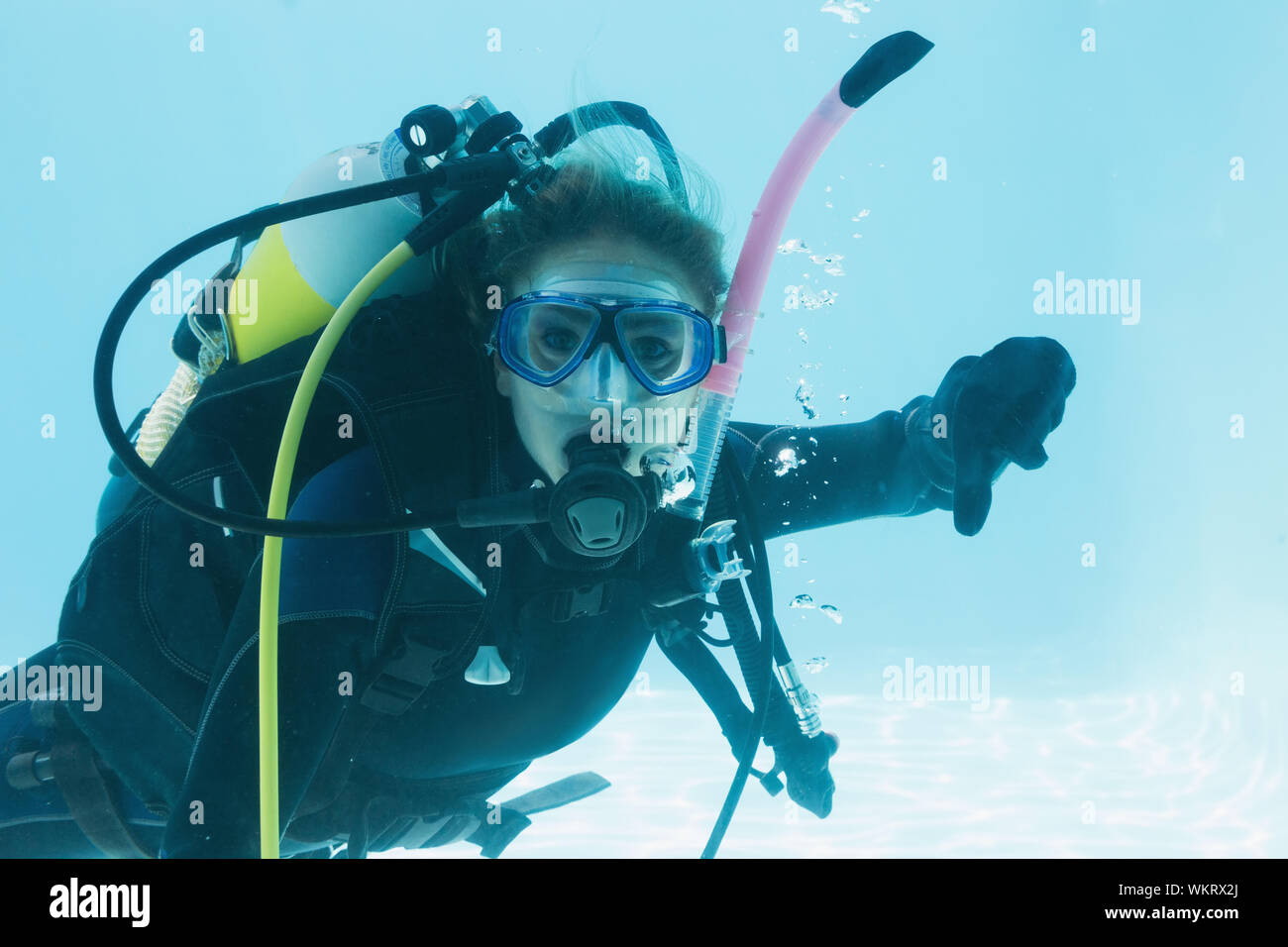 Frau auf scuba Training im Schwimmbad Daumen nach unten zeigen auf ihren Urlaub unter Wasser Stockfoto