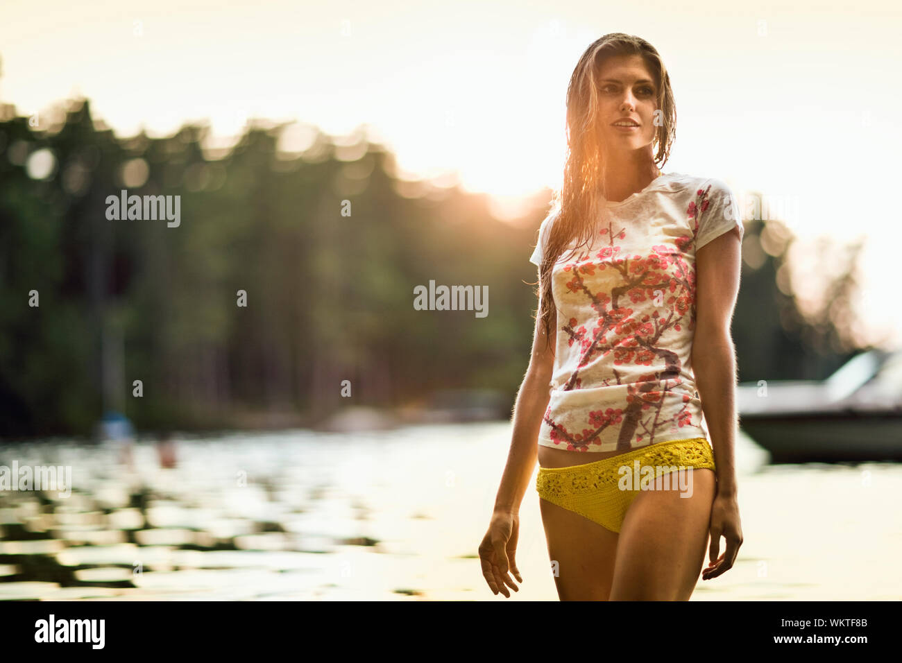 Schöne junge Frau trägt einen gelben Bikini Bottom und t-shirt in einem See. Stockfoto