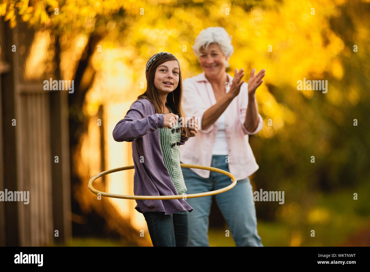 Ältere Frau Uhren ihrer Enkelin hooping hula. Stockfoto
