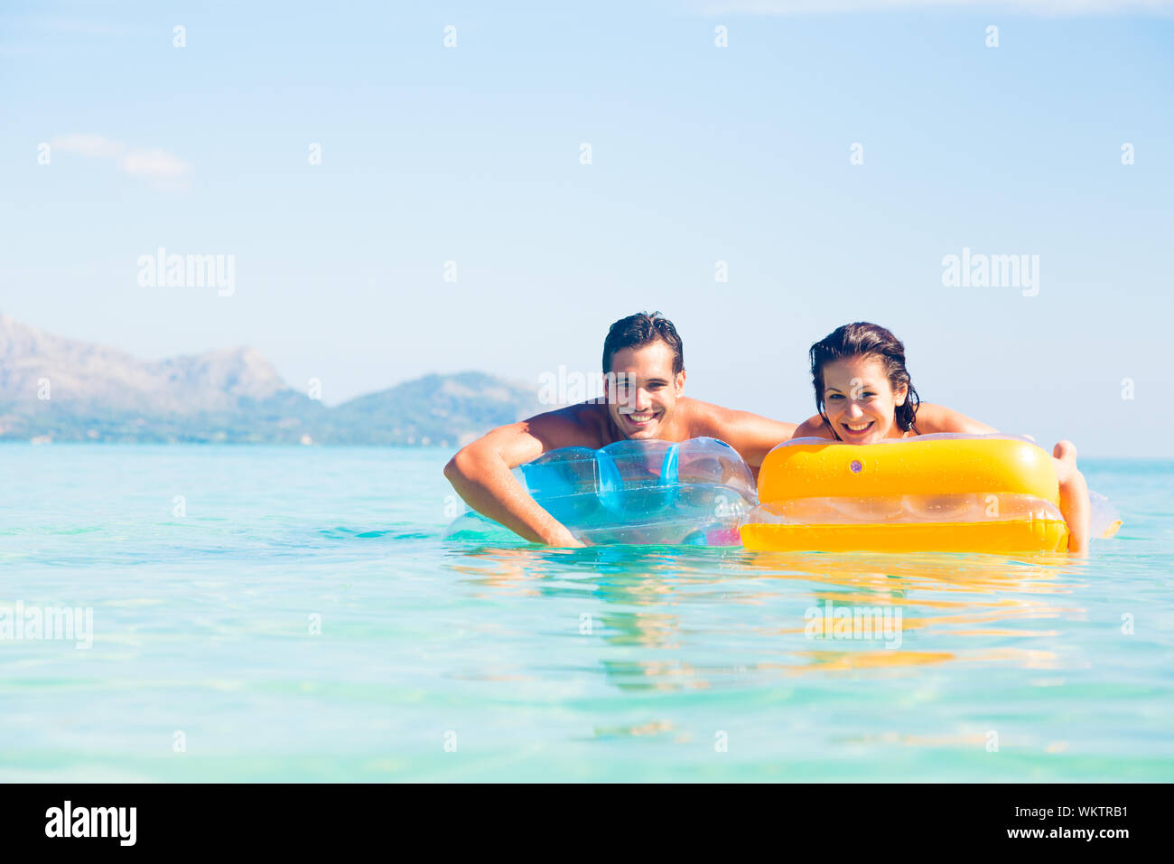 Porträt eines jungen Paares schwimmende aufblasbare Flöße im Meer gegen Sky Stockfoto