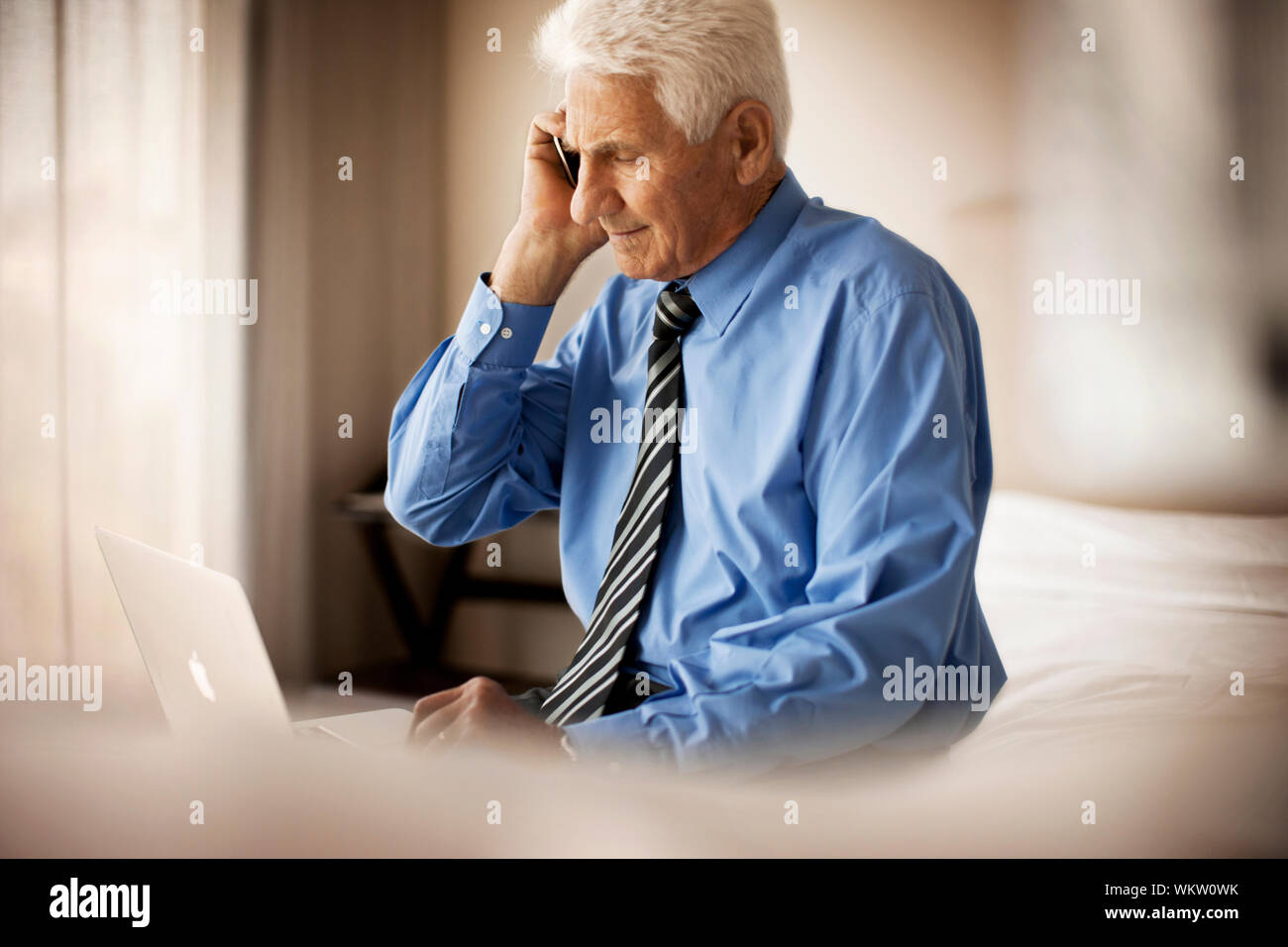 Senior Geschäftsmann Gespräche über ein Mobiltelefon, während er auf dem Bett. Stockfoto