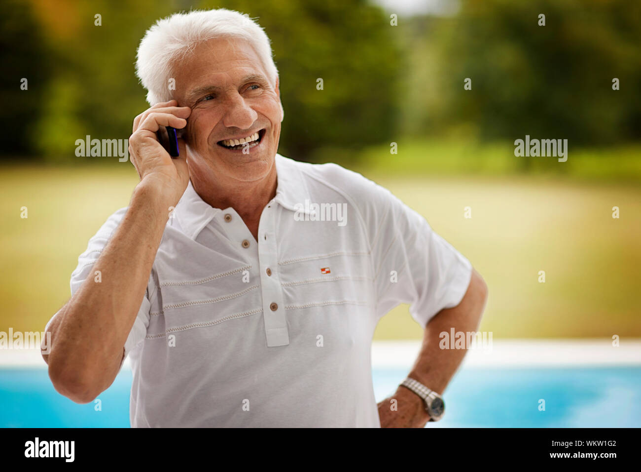 Älterer Mann lächelt, als er auf einem Mobiltelefon Gespräche. Stockfoto