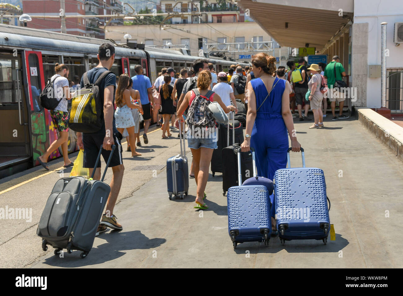 SORRENTO, ITALIEN - AUGUST 2019: Leute, Koffer Ziehen entlang einer Plattform nach der Ankunft am Bahnhof von Sorrento. Stockfoto