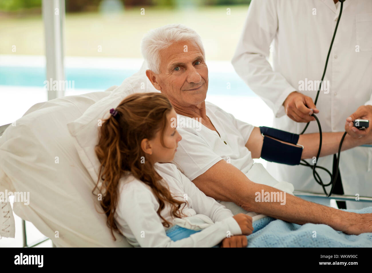 Der Mensch seinen Blutdruck in ein Krankenhaus gebracht, während ein Besuch von seiner Enkelin. Stockfoto