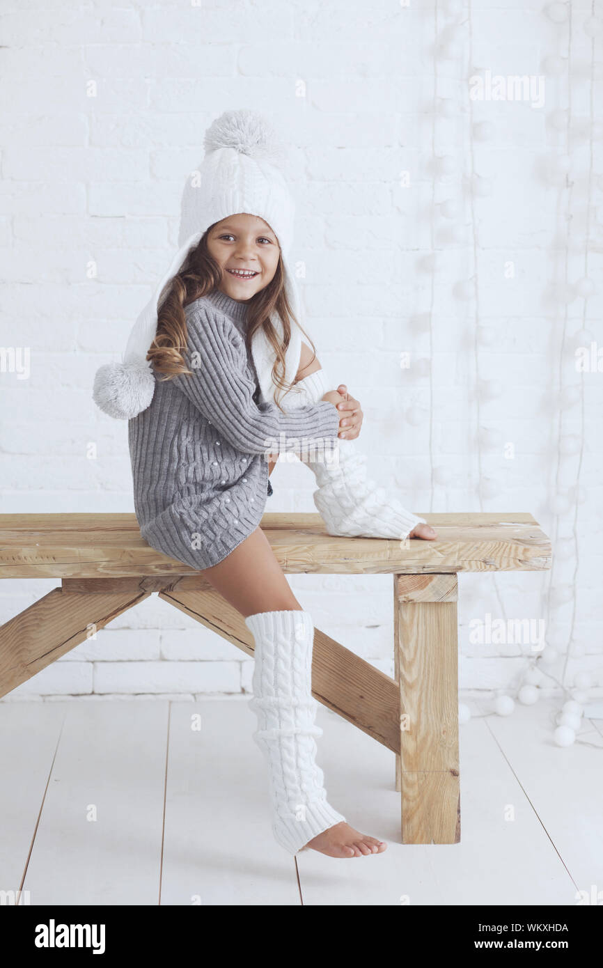 Süßes kleines Mädchen 5 Jahre alt, aus Gewirken trendy Winter Kleidung über  weiße Mauer posing Stockfotografie - Alamy