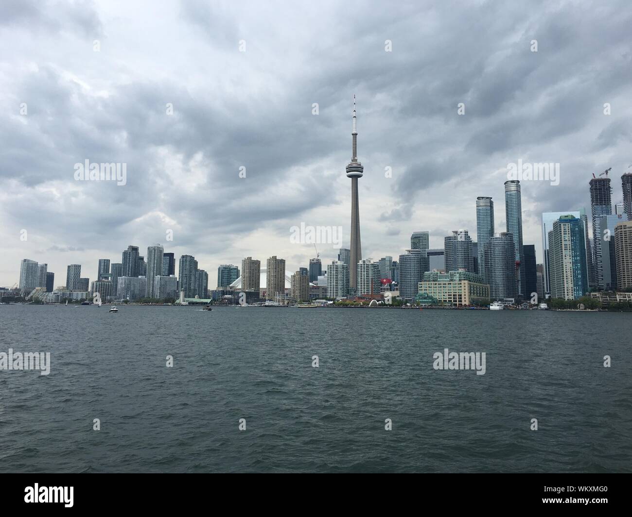 Cn Tower von Fluss gegen bewölkten Himmel in der Stadt Stockfoto