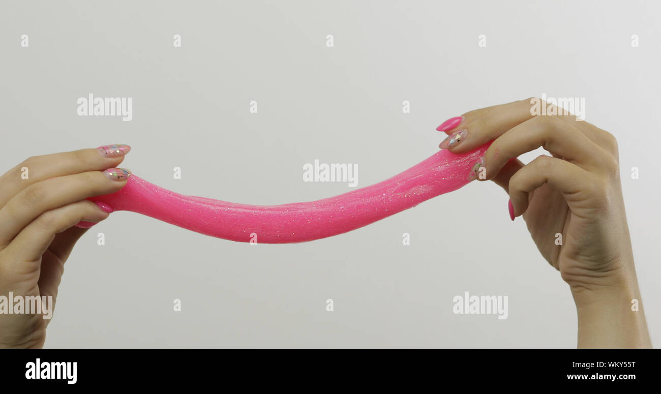 Frau Hände spielen mit ungewöhnlich befriedigend rosa Schleim auf weißen  Hintergrund. Klebrige klebrige Substanz. Entspannen und auf unerklärliche  Weise zufriedenstellend. Super virale Trend auf Social Media für antistress  Dinge Stockfotografie