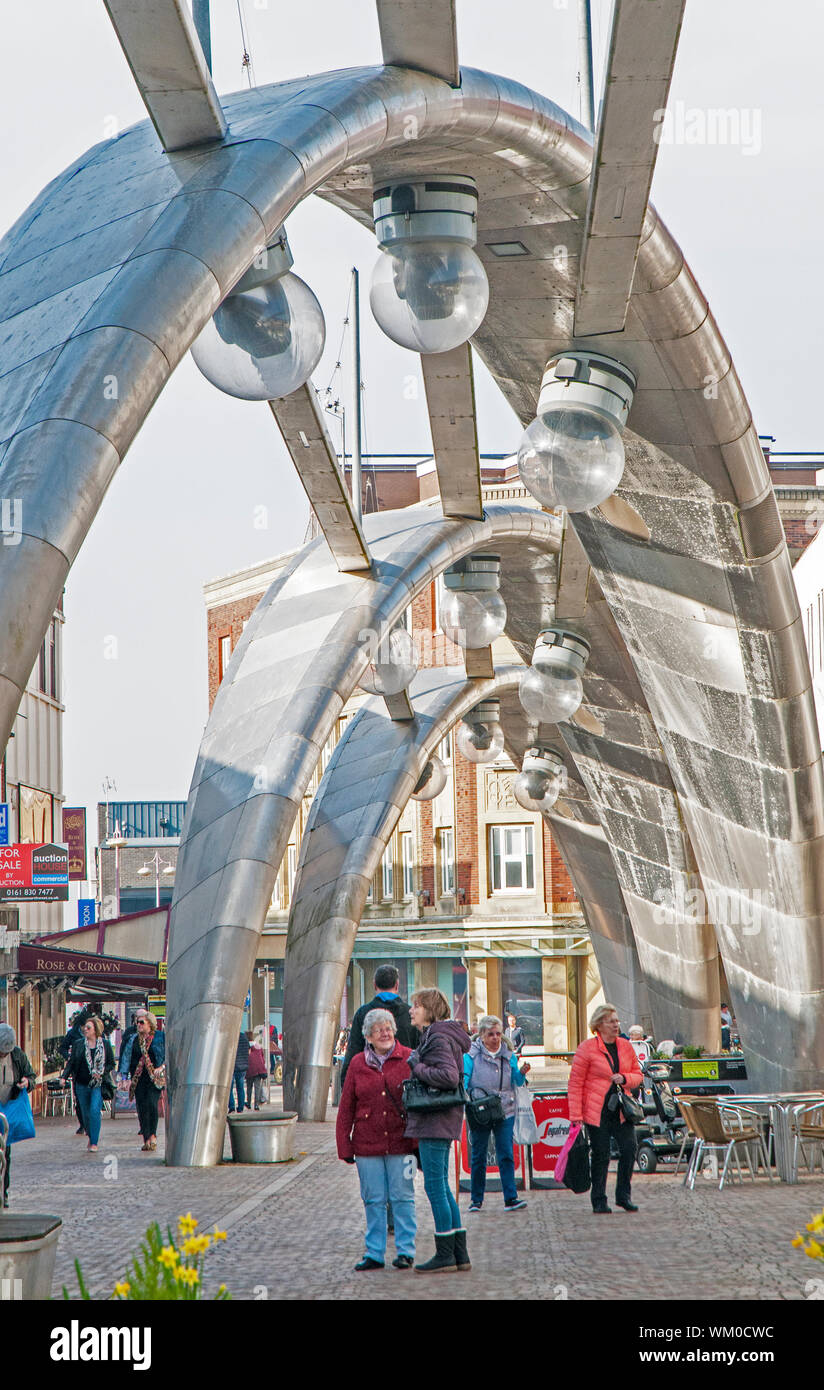 Zwei Damen, die ständigen Gespräch unter modernen futuristische Edelstahl Projektion Beleuchtung in Blackpool, Lancashire, England UK Bögen Stockfoto