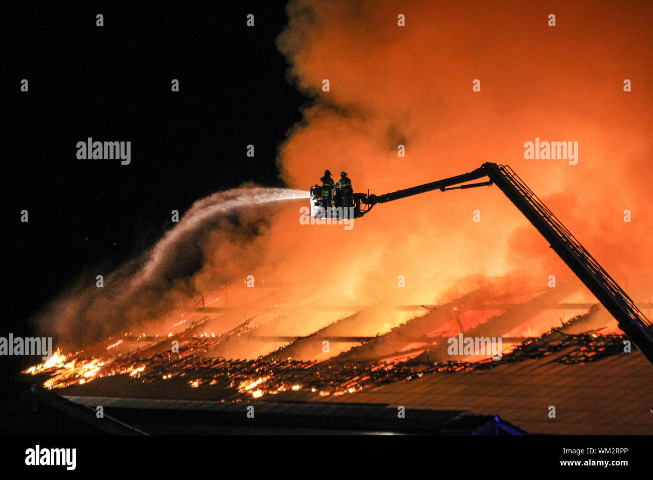 Aachen, Deutschland. 05 Sep, 2019. Feuerwehrmänner der Feuerwehr Kampf der Brand einer Scheune neben einer Reithalle im Neuhaus Immobilien von einer Leiter. Das Gebäude mit rund 3500 Ballen Stroh und Heu gelagert ist auf Feuer, sagte ein Sprecher der Feuerwehr. Trotz der Größe des Feuers, die insgesamt etwa 100 Feuerwehrleute schnell den Brand unter Kontrolle. Es bestand keine Gefahr für die Tiere oder Menschen. Die Feuerwehr brachte die Pferde aus der benachbarten Reithalle zur Sicherheit. Credit: Ralf Roeger/dpa/Alamy leben Nachrichten Stockfoto