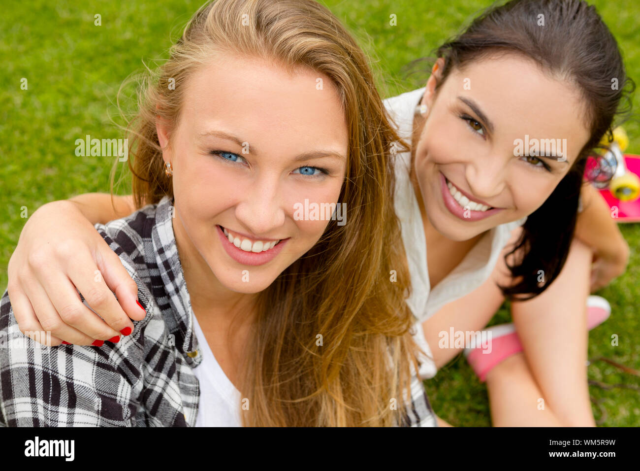 Teens beste Freunde sitzen auf dem Rasen Lächeln auf den Lippen und eine gute Zeit Stockfoto