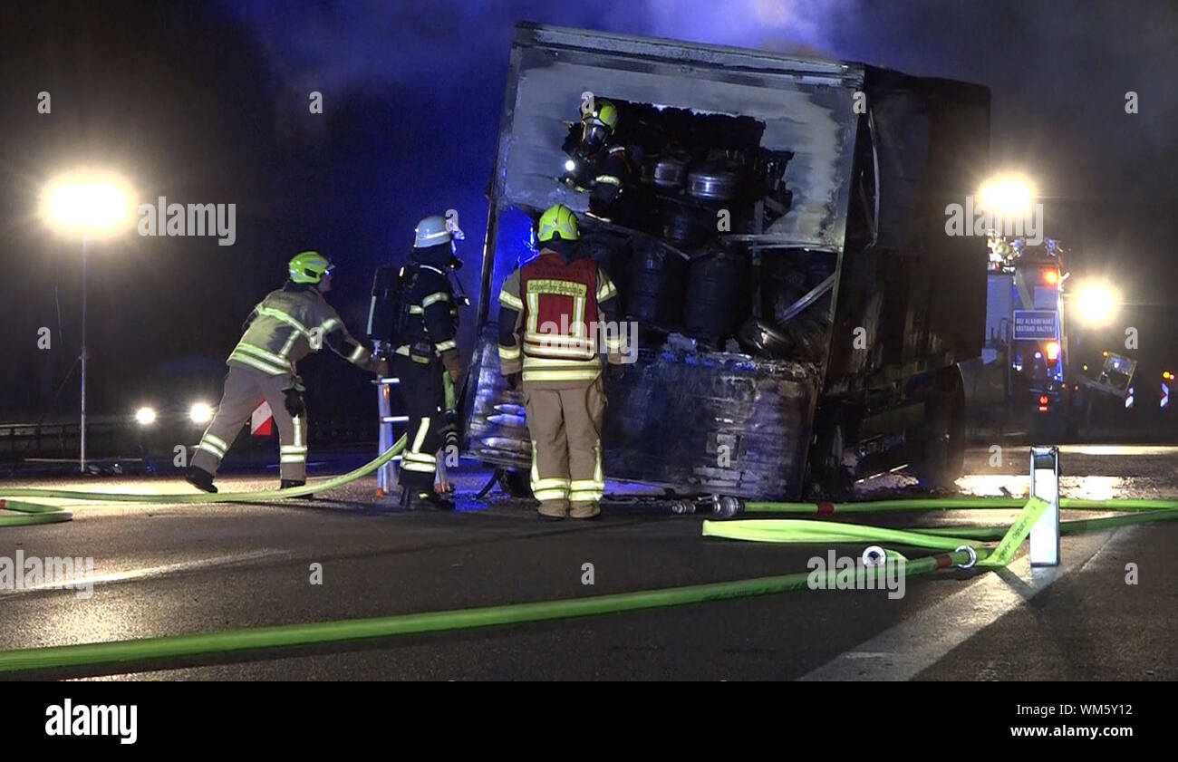 05. September 2019, Niedersachsen, Osnabrück: Feuerwehrmänner erholen der Anhänger eines Lkw mit 5000 Liter Bier, die komplett auf der Autobahn 1 gebrannt wird. Der Fahrer das Feuer bemerkt und Links die brennenden Anhänger in eine Baustelle am späten Mittwoch Abend, sagte die Polizei. Nach Angaben der Polizei wurde das Feuer vermutlich durch einen technischen Defekt zurückzuführen. Der 57-Jährige war in der Lage, sich selbst und der Auflieger auf 200 Meter weiter in Sicherheit zu bringen. Foto: Nord-West-Media/dpa Stockfoto