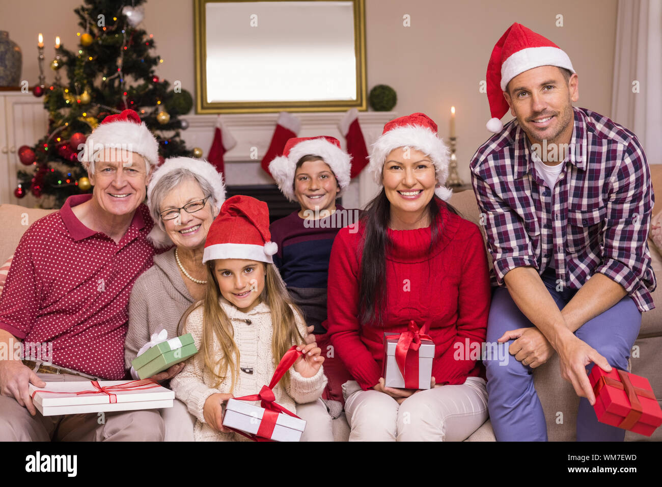 Multigeneration Familie tragen Nikolausmützen auf der Couch zu Hause im Wohnzimmer Stockfoto