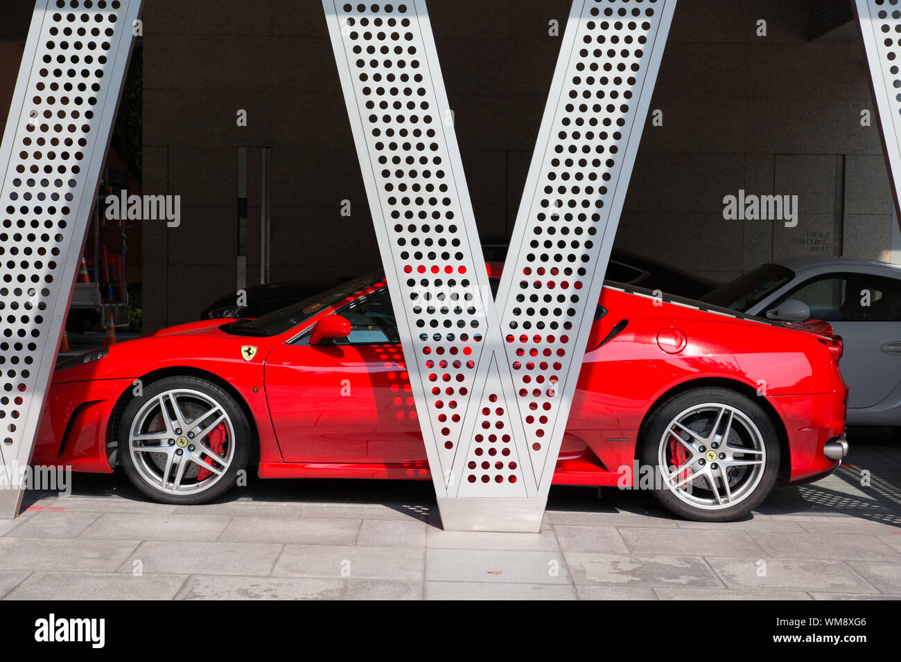 Ein roter Ferrari-Parkplatz hinter einem V-Säulen-Unterstand. Singapur Stockfoto