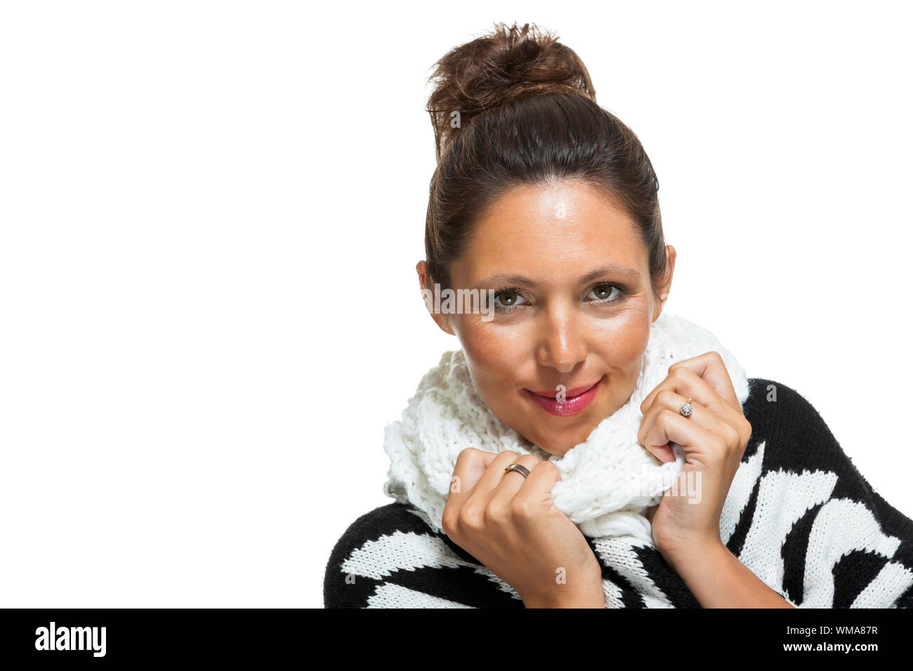 Attraktive elegante Frau im Winter Mode, kuschelte sich in ihre weißen Schal und schwarzen und weißen Jumper nicht den kalten Winter Wetter, auf Pfingstmontag auf Station Stockfoto